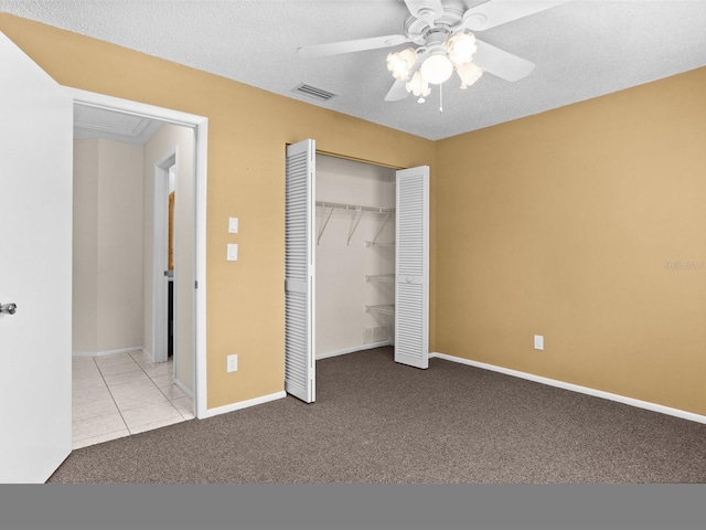 unfurnished bedroom with a textured ceiling, light carpet, visible vents, baseboards, and a closet