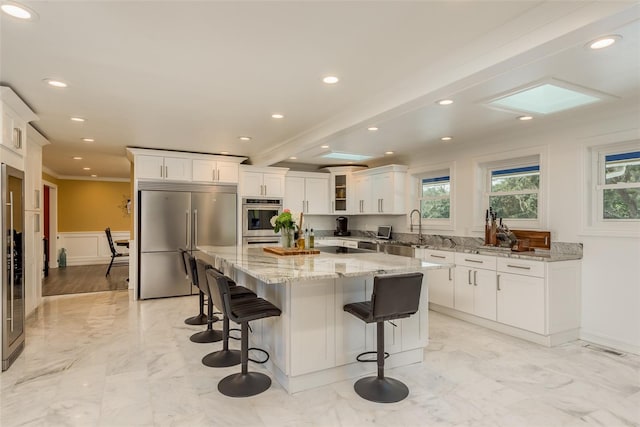 kitchen featuring a center island, stainless steel built in refrigerator, white cabinetry, and light hardwood / wood-style floors