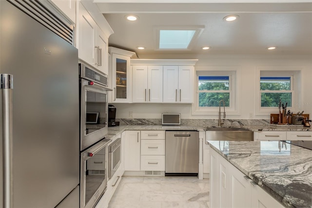 kitchen featuring appliances with stainless steel finishes, crown molding, light tile patterned flooring, and light stone countertops