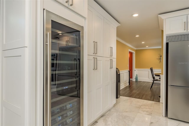 kitchen featuring light hardwood / wood-style floors, white cabinetry, stainless steel built in fridge, and crown molding