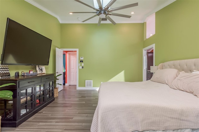 bedroom with hardwood / wood-style flooring, ornamental molding, a towering ceiling, and ceiling fan