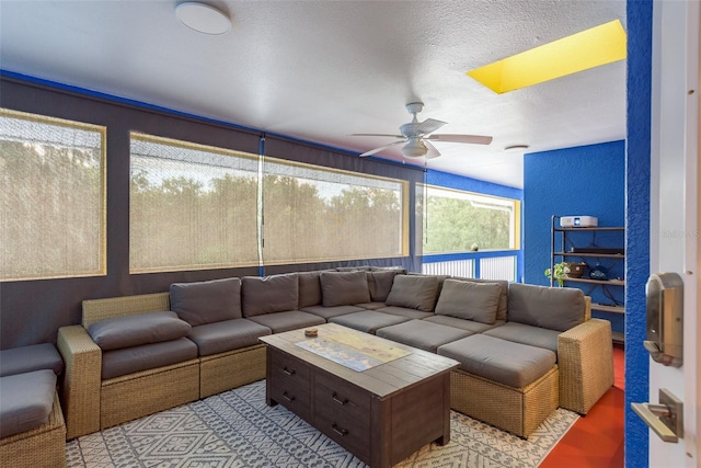 living room featuring ceiling fan and a textured ceiling