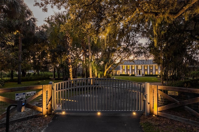 gate at dusk featuring a lawn