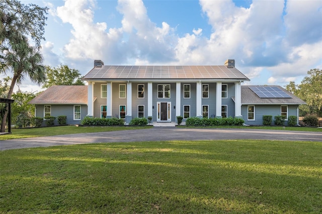 greek revival inspired property with solar panels and a front lawn