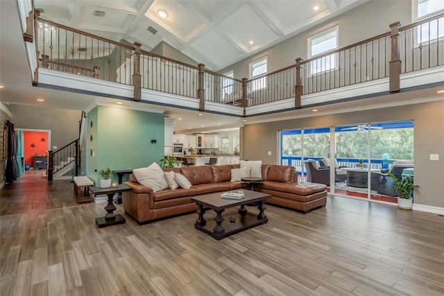 living room featuring a high ceiling, light hardwood / wood-style flooring, and coffered ceiling