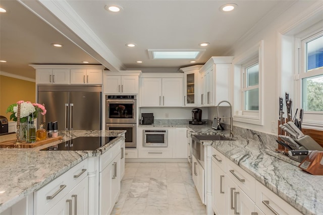 kitchen with white cabinets, light stone counters, light tile patterned floors, crown molding, and stainless steel appliances