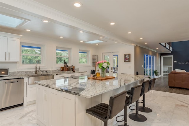 kitchen with light stone counters, a center island, and dishwasher