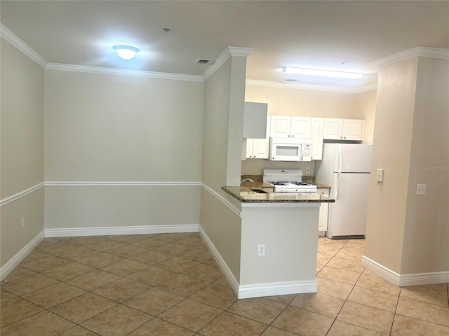 kitchen with dark stone countertops, white appliances, light tile patterned floors, kitchen peninsula, and ornamental molding