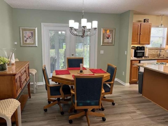 dining room with a textured ceiling, light hardwood / wood-style flooring, an inviting chandelier, and plenty of natural light