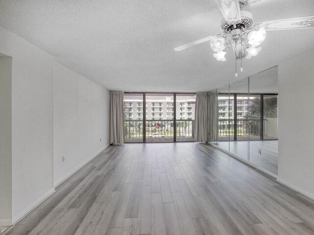 unfurnished room with floor to ceiling windows, ceiling fan, a textured ceiling, and light hardwood / wood-style floors