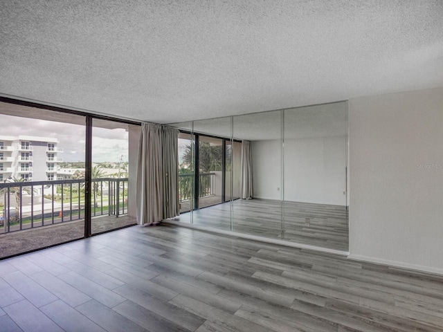 empty room with light hardwood / wood-style flooring, expansive windows, and a textured ceiling