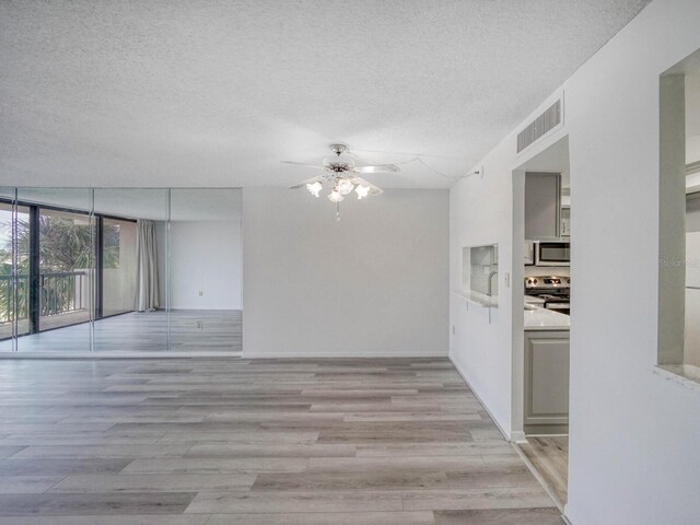 empty room with ceiling fan, light hardwood / wood-style floors, and a textured ceiling