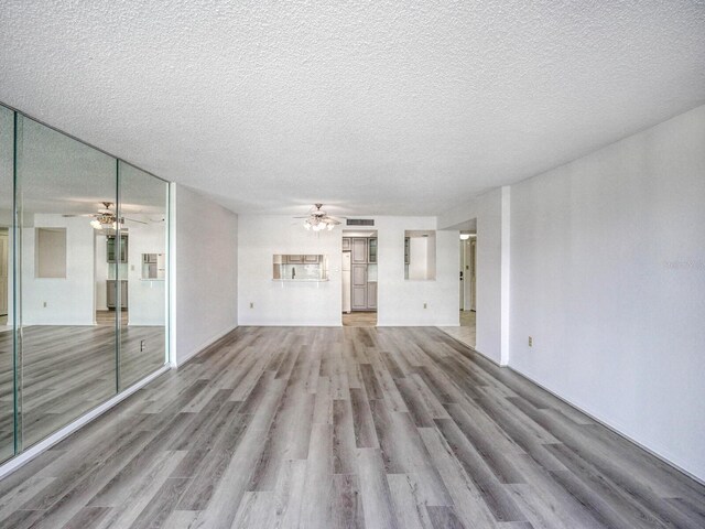 unfurnished living room featuring hardwood / wood-style flooring, ceiling fan, and a textured ceiling