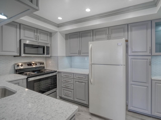 kitchen with ornamental molding, appliances with stainless steel finishes, light stone countertops, and gray cabinetry