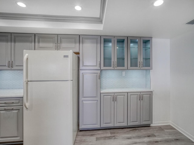 kitchen featuring tasteful backsplash, crown molding, white fridge, and gray cabinetry