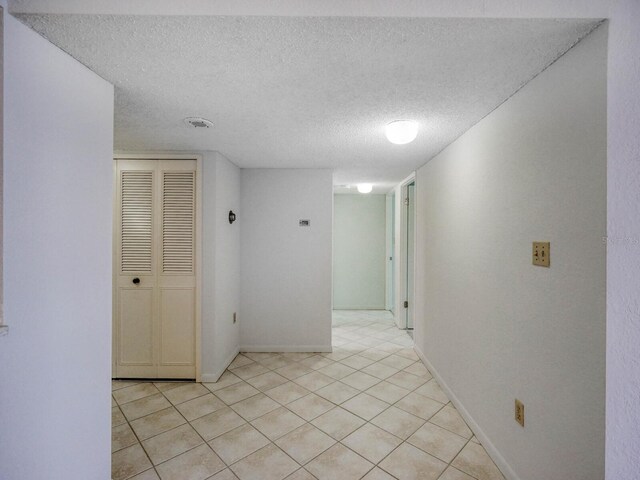 corridor with light tile patterned floors and a textured ceiling