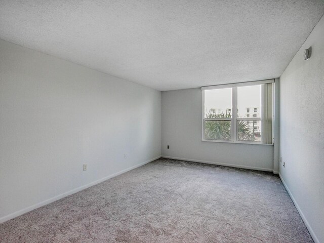 carpeted empty room with a textured ceiling