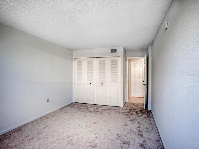 unfurnished bedroom featuring a closet, light carpet, and a textured ceiling