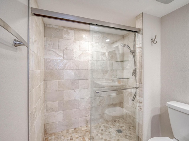 bathroom featuring toilet and a shower with shower door