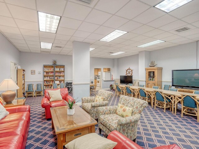 living room with a paneled ceiling and carpet flooring