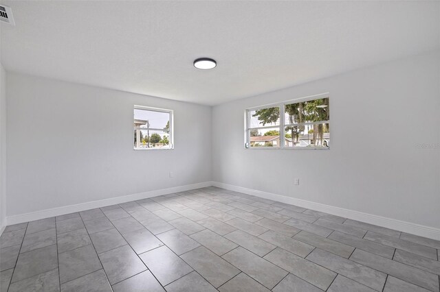 tiled empty room featuring plenty of natural light