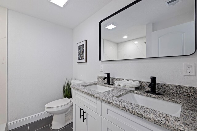 bathroom with toilet, double sink vanity, and tile patterned flooring