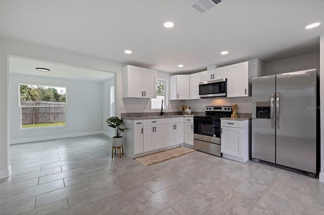 kitchen featuring light tile patterned flooring, white cabinetry, light stone counters, and appliances with stainless steel finishes