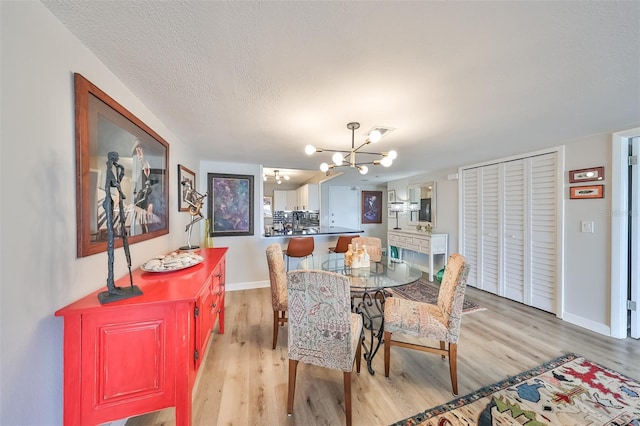 dining space with a chandelier, light hardwood / wood-style flooring, and a textured ceiling