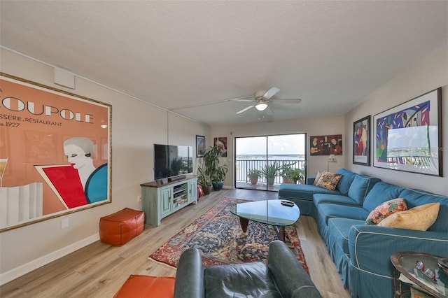 living room featuring ceiling fan, a textured ceiling, and light hardwood / wood-style flooring