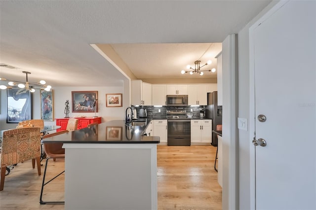 kitchen featuring stainless steel appliances, decorative light fixtures, kitchen peninsula, and white cabinets