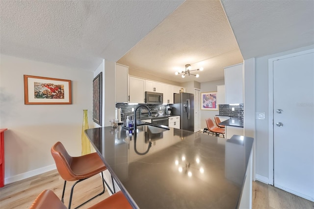 kitchen with appliances with stainless steel finishes, kitchen peninsula, white cabinets, and decorative backsplash