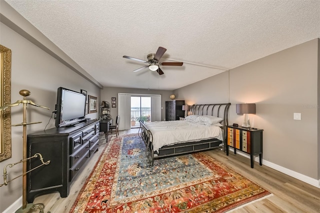 bedroom with ceiling fan, wood-type flooring, a textured ceiling, and access to outside