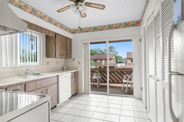 kitchen with plenty of natural light, dishwasher, light tile patterned flooring, and wall chimney range hood