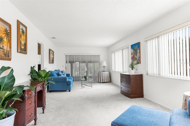 living area featuring light carpet and a textured ceiling