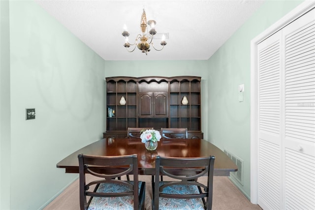 carpeted dining area with a chandelier and a textured ceiling