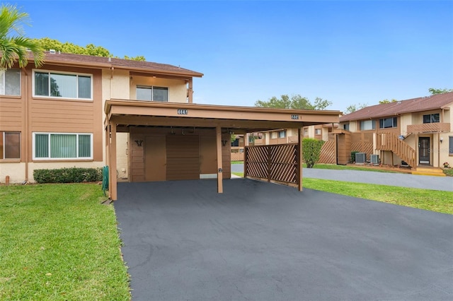 view of front of house with a carport, a front yard, and central air condition unit