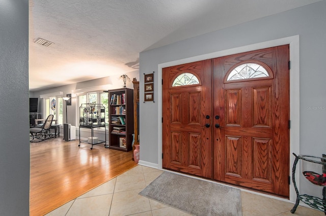 foyer entrance with a textured ceiling and light hardwood / wood-style flooring