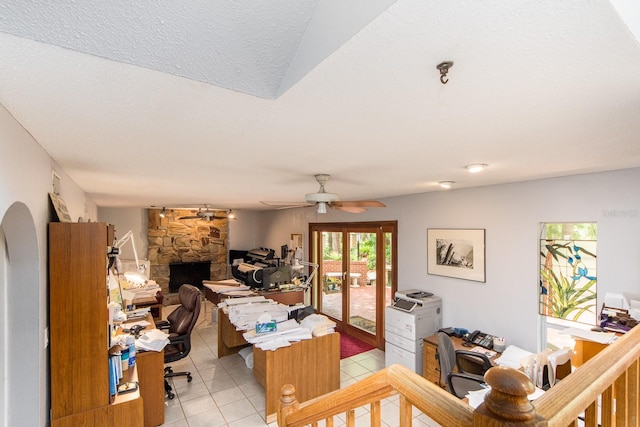 tiled living room with a textured ceiling, a fireplace, and ceiling fan