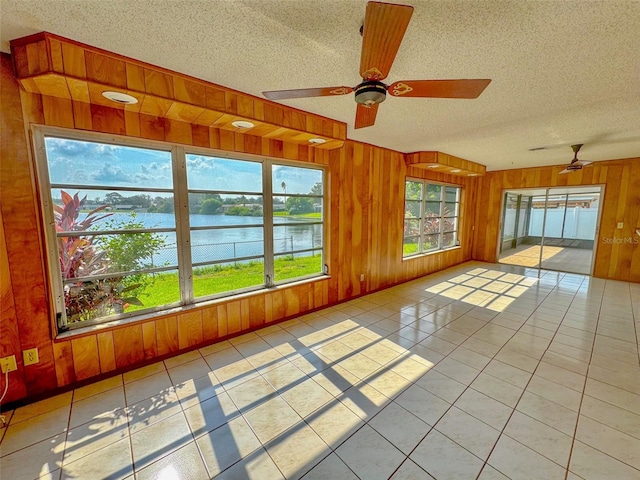 unfurnished sunroom with a ceiling fan and a water view