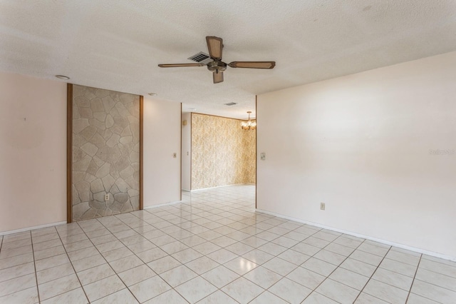 empty room with light tile patterned floors, ceiling fan with notable chandelier, visible vents, and a textured ceiling