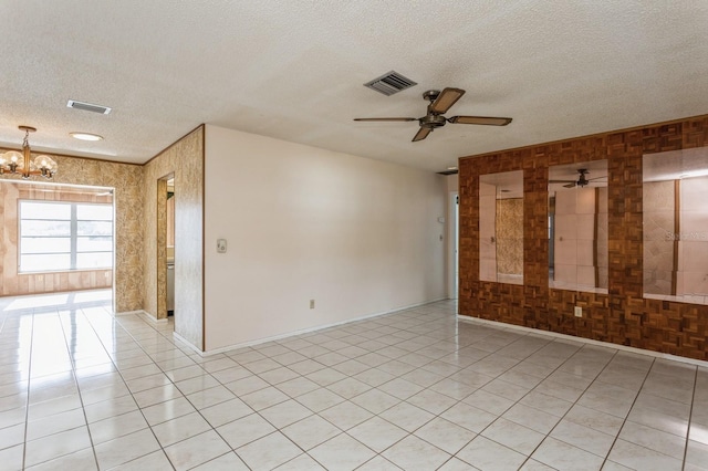 unfurnished room with light tile patterned floors, visible vents, ceiling fan with notable chandelier, and a textured ceiling