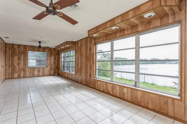 unfurnished sunroom with visible vents, ceiling fan, and a water view