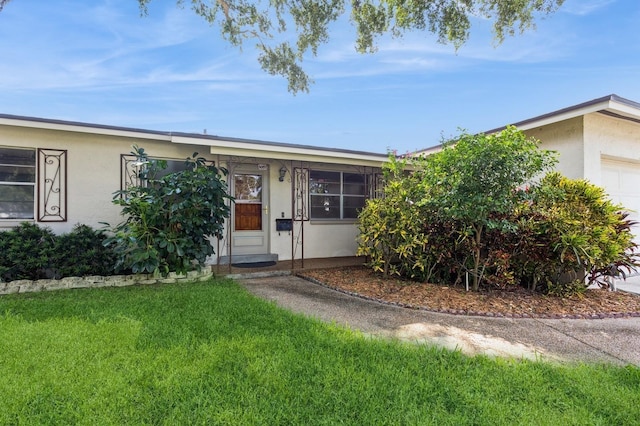 ranch-style house featuring stucco siding, an attached garage, and a front lawn