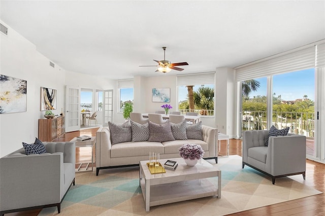 living room with plenty of natural light, light hardwood / wood-style floors, and ceiling fan