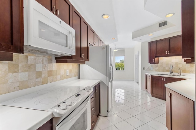 kitchen featuring backsplash, sink, light tile patterned floors, and white appliances