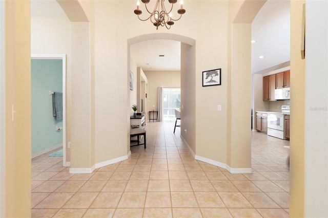 hallway featuring light tile patterned flooring and an inviting chandelier