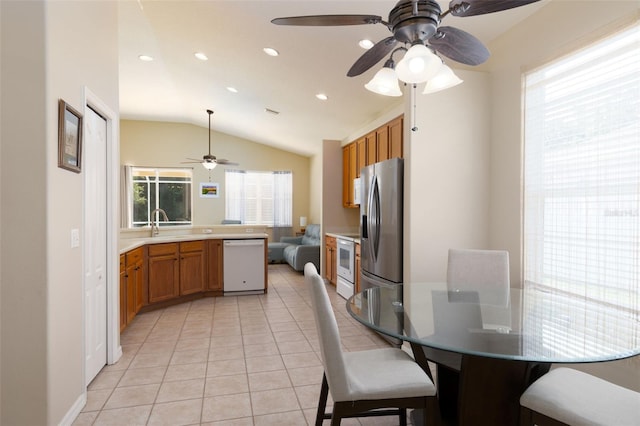 dining area with ceiling fan, vaulted ceiling, and light tile patterned floors