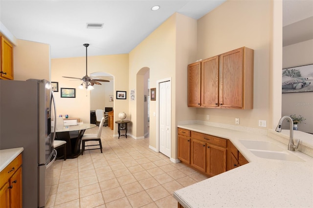 kitchen with light tile patterned flooring, ceiling fan, sink, stainless steel refrigerator with ice dispenser, and high vaulted ceiling