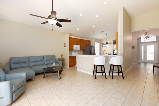 tiled living room with ceiling fan with notable chandelier and vaulted ceiling