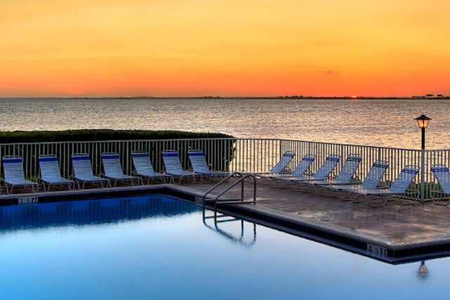 pool at dusk featuring cooling unit and a water view